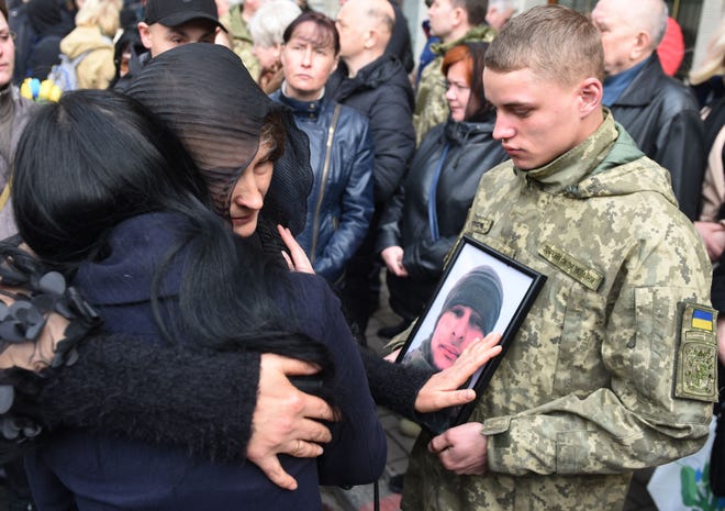 I parenti abbracciano il funerale del soldato ucraino Theodore Osadchy al cimitero di Lychakiv a Leopoli, nell'Ucraina occidentale, il 29 marzo 2022.