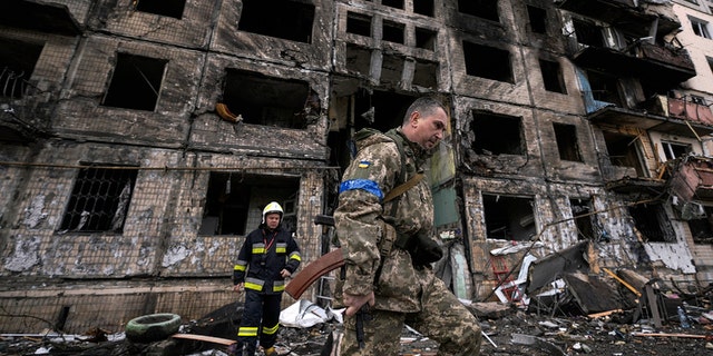 Soldati e vigili del fuoco ucraini ispezionano un edificio distrutto dopo un attentato dinamitardo a Kiev, in Ucraina, lunedì 14 marzo 2022. 