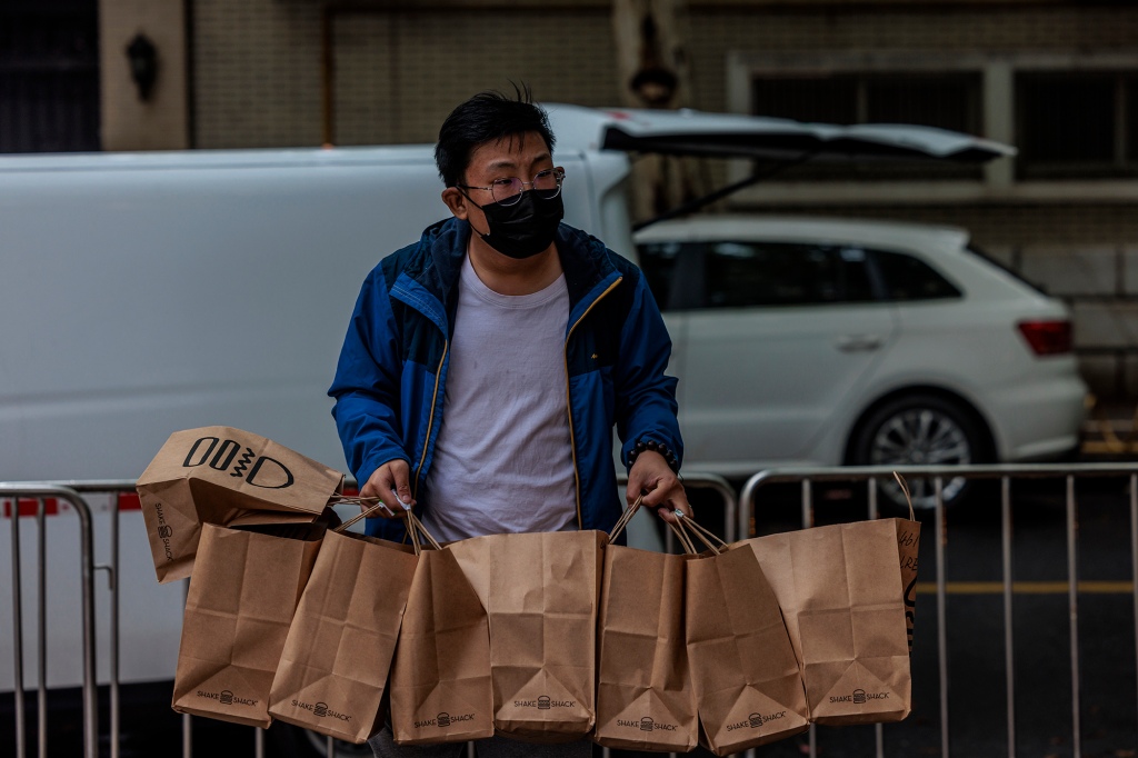 Un addetto alle consegne porta cibo in una comunità residenziale chiusa a Shanghai, Cina, 23 aprile 2022.