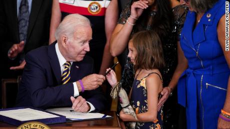Il presidente degli Stati Uniti Joe Biden consegna la penna di Brill Robinson, figlia del sergente.  Heath Robinson di prima classe, mentre sua madre, Danielle Robinson, posa al suo fianco durante una 