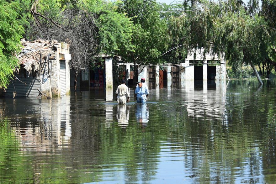 I residenti guadano nelle acque alluvionali vicino alle loro case dopo le forti piogge monsoniche.