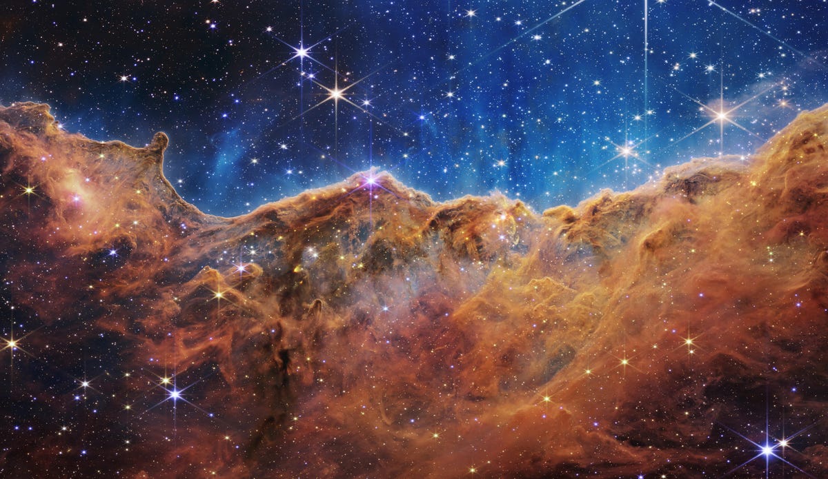 La nebulosa della Carina: le stelle brillano su uno sfondo indaco sopra nubi di gas color bronzo arrugginito