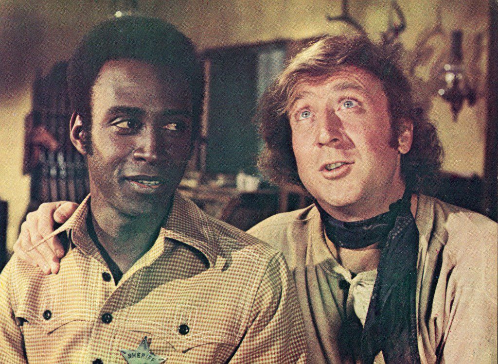 Gene Wilder (a destra) mette un braccio intorno alla spalla di Cleavon Little in un fotogramma del film, "selle ardenti," Regia di Mel Brooks, 1974.