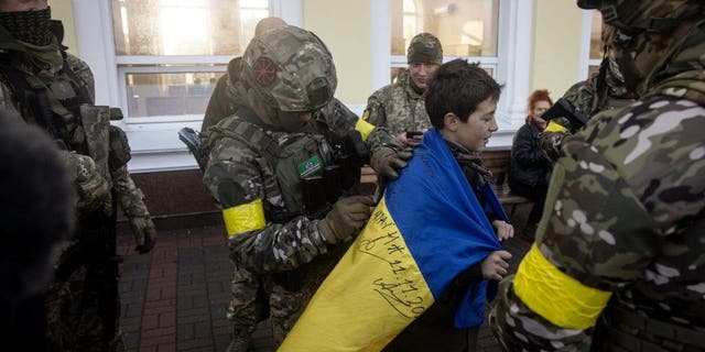 Un ragazzo tiene la sua bandiera nazionale ucraina firmata dai membri dell'esercito ucraino, 19 novembre 2022, a Kherson, Ucraina.